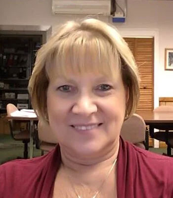 Village of Painted Post Clerk-Treasurer Anne Names sitting in a chair with blond short hair and a red shirt on